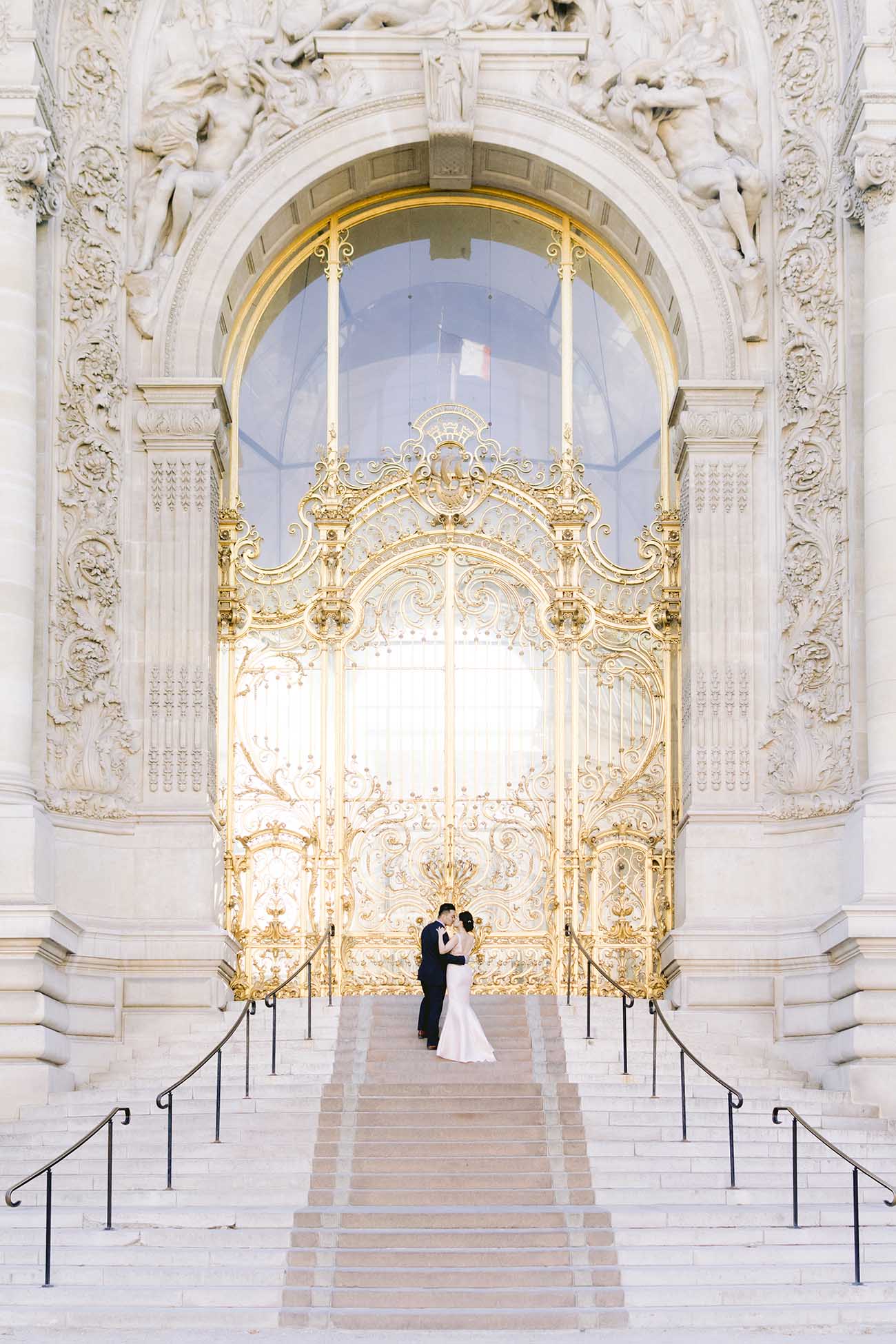  A couple embraces in front of the magnificent golden door of the Petit Palais in Paris